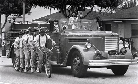 Firefighters Riding 5-person Bicycle next to Old Fire Engine